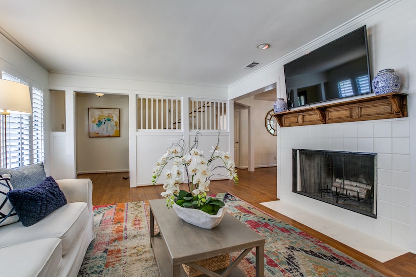 A living room features a white fireplace and coffee table with an orchid.