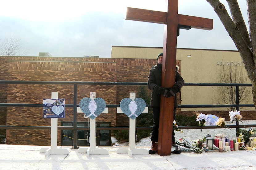 Dan Beazley stands with the homemade cross he brought from Michigan for victims of a...