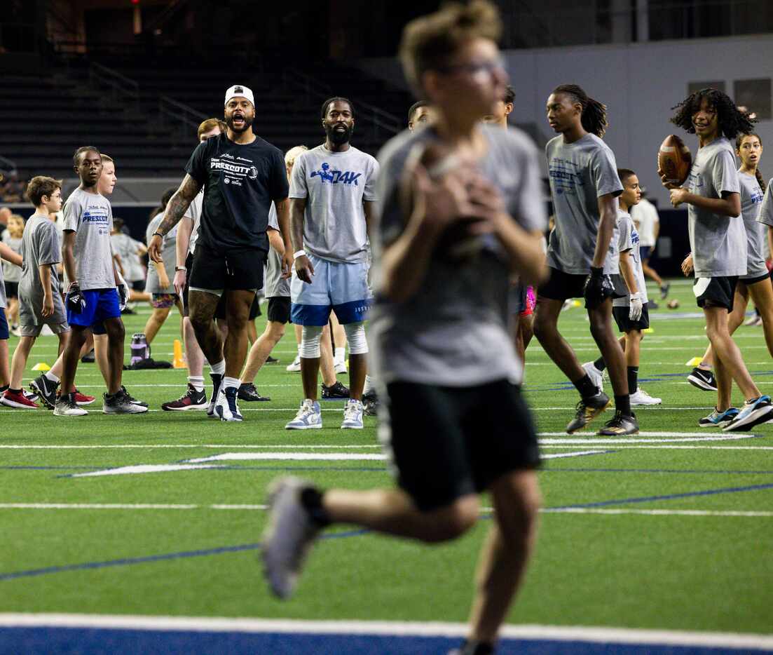 Cowboys quarterback Dak Prescott cheers after a student completes a pass while running...