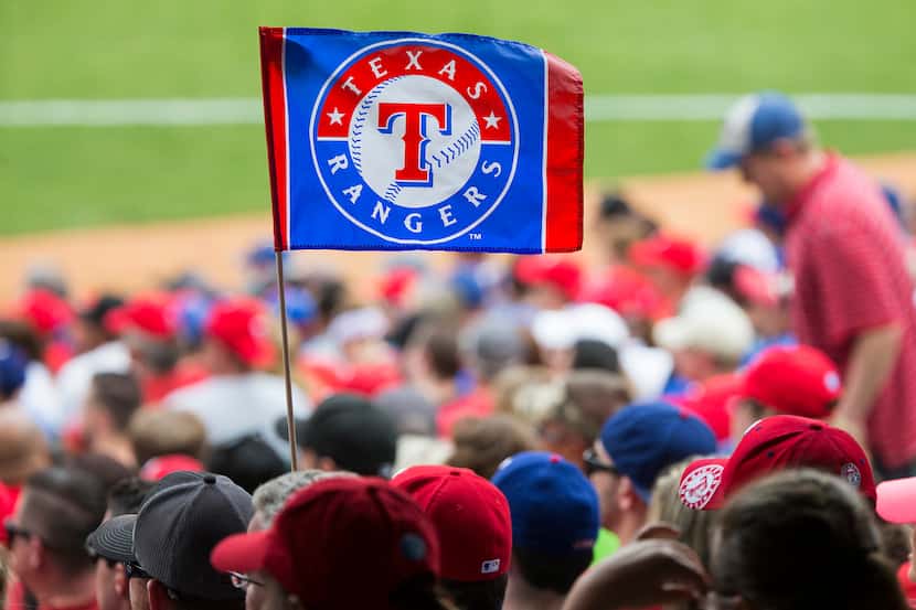 Texas Rangers fans hold a team flag during the ninth inning against the Houston Astros at...