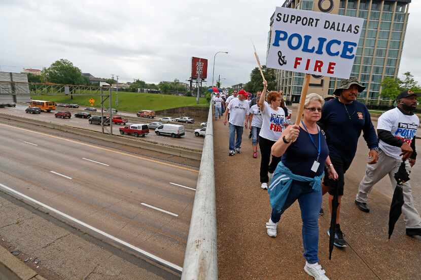 Dallas police and fire retirees march on Akard Street to City Hall in Dallas on April 26,...