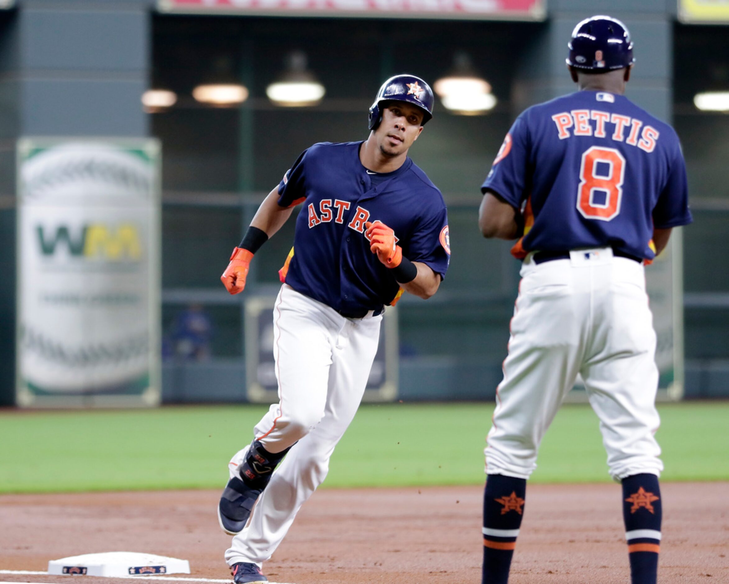 Houston Astros left fielder Michael Brantley, left, rounds third base as third base coach...