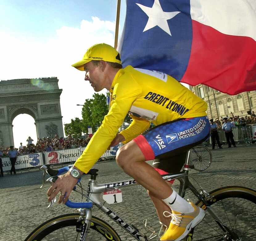 Lance Armstrong rides past the Arc de Triomphe waving the Texas flag after he won the Tour...