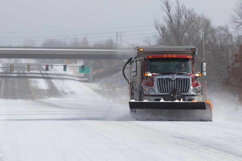 A Kansas Department of Transportation snow plow truck scrapes away layers of snow and ice...