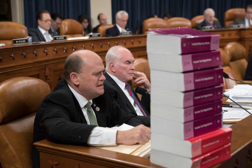 Seated behind a stack of IRS and tax volumes, Rep. Tom Reed, R-N.Y., left, joined by Rep....