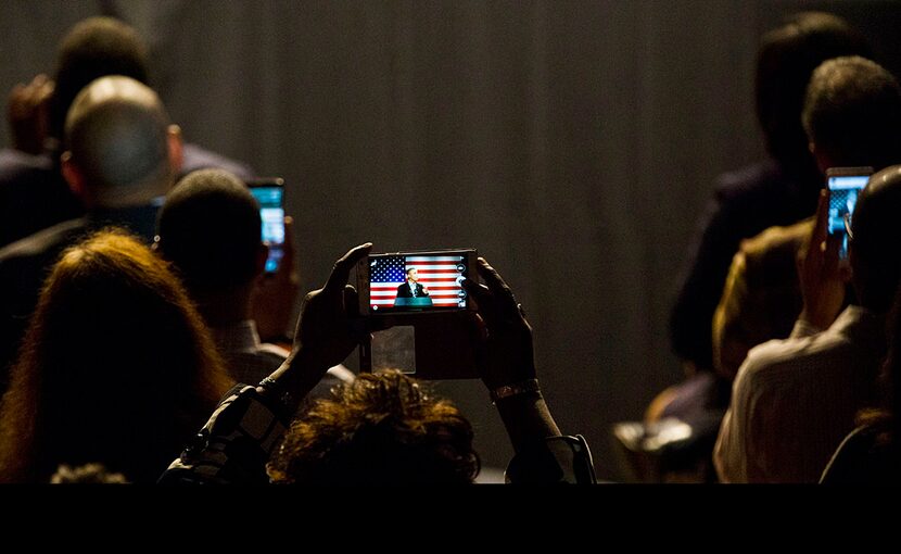  A woman takes a photo of President Barack Obama as he speaks at a Democratic National...