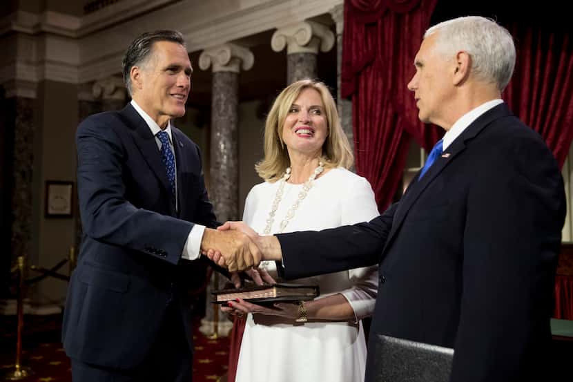 Vice President Mike Pence shakes hands with Sen. Mitt Romney, R-Utah, accompanied by his...