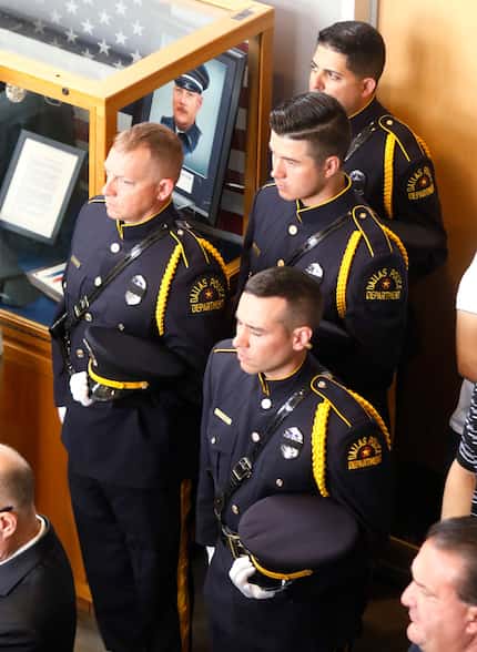 Dallas Police Officers stand at attention next to a display case honoring DART Police...