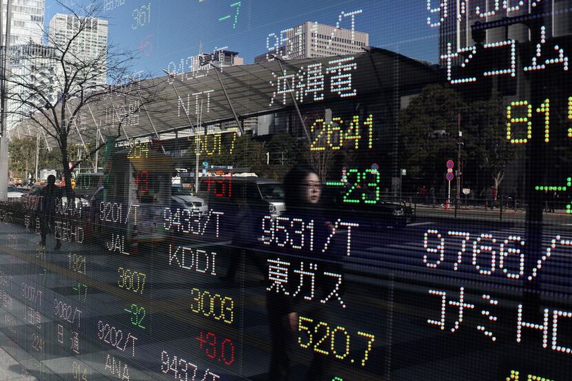A woman is reflected on an electronic stock indicator of a securities firm in Tokyo,...