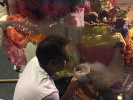  A man blows copal incense into the night air around an altar at Dallas Continental bridge...