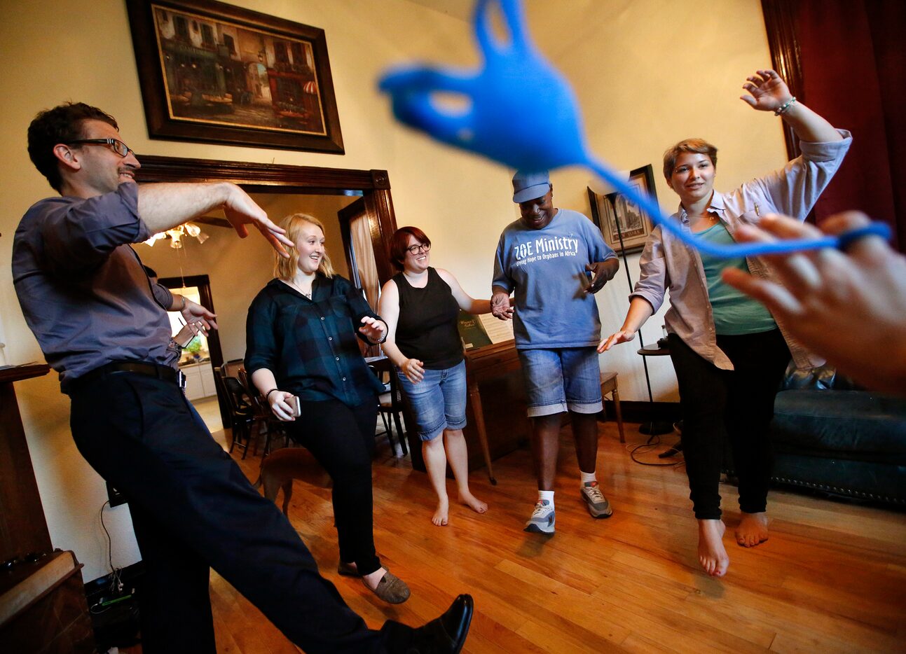 Before a dinner prayer, SMU student Amber Oxley (right) leads group yoga with residents and...