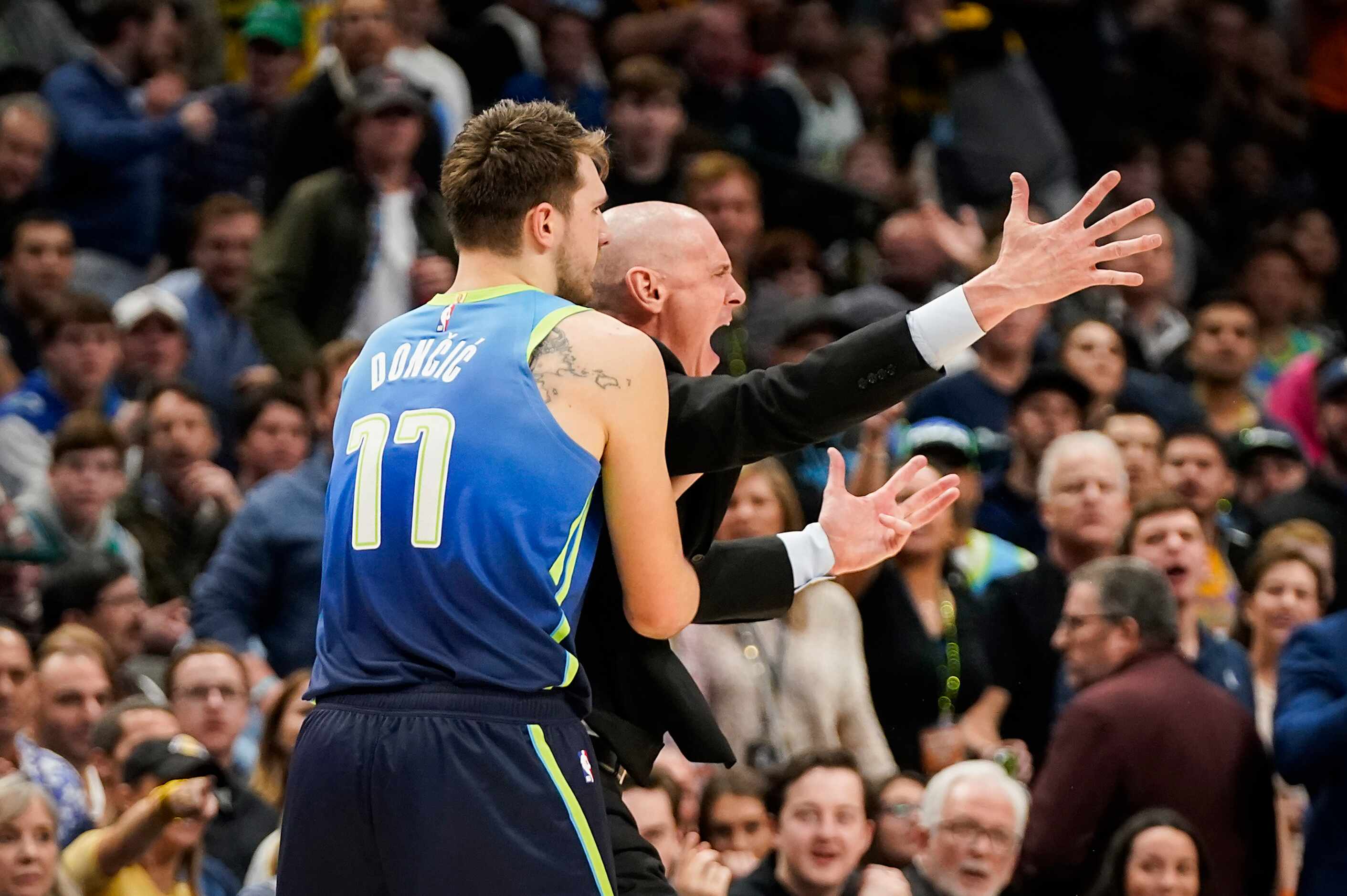 Dallas Mavericks head coach Rick Carlisle is restrained by guard Luka Doncic after being...