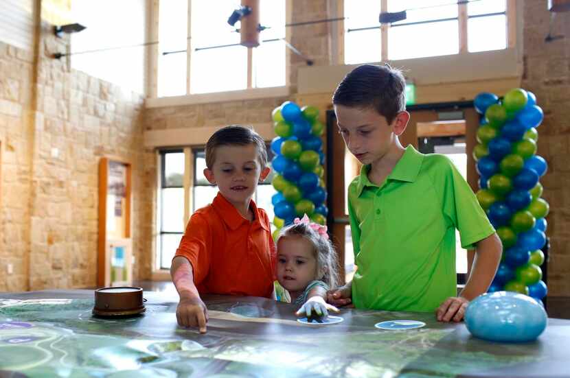 
Kenny, 7 (left), Savina, 2, and Jacob Smith, 11, look at the interactive map in the new Oak...