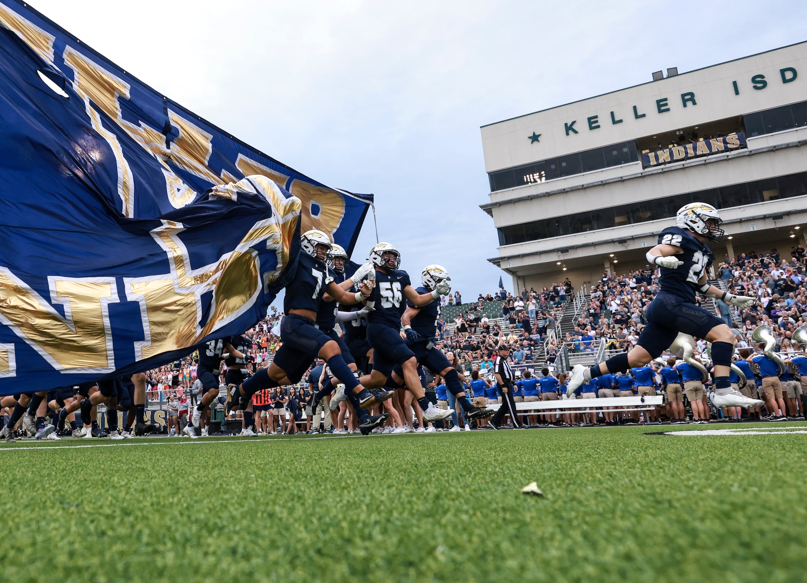 Keller High School players run on the field before the football game between Keller High...