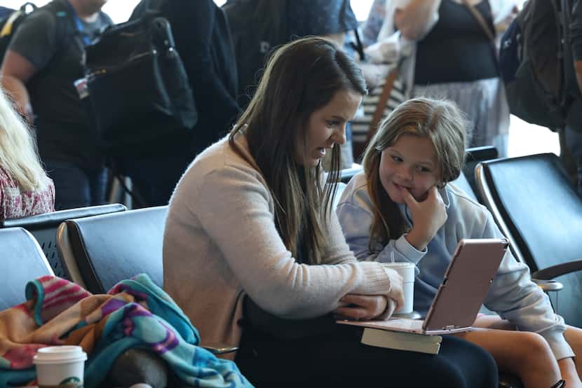 Lynnae Shubert and her daughter Brynn, 10, look at a laptop while waiting for their flight...