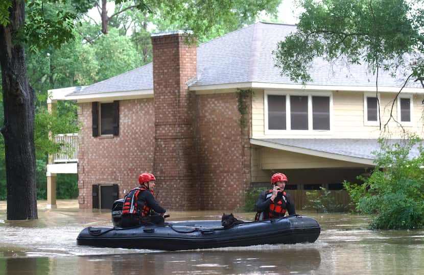 Emergency workers with Caney Creek Fire and Rescue carry a dog from a flooded area in the...