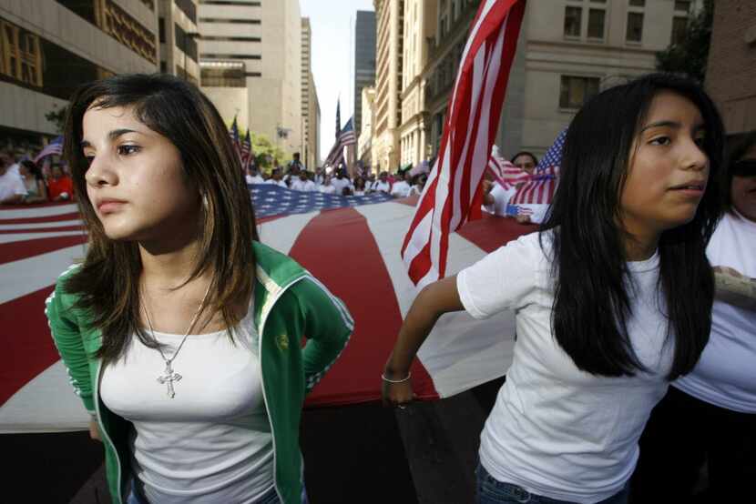 Vickie Ojeda, 15, (right) and Stephanie Hernandez, 15, (left) carry the flag as they make...