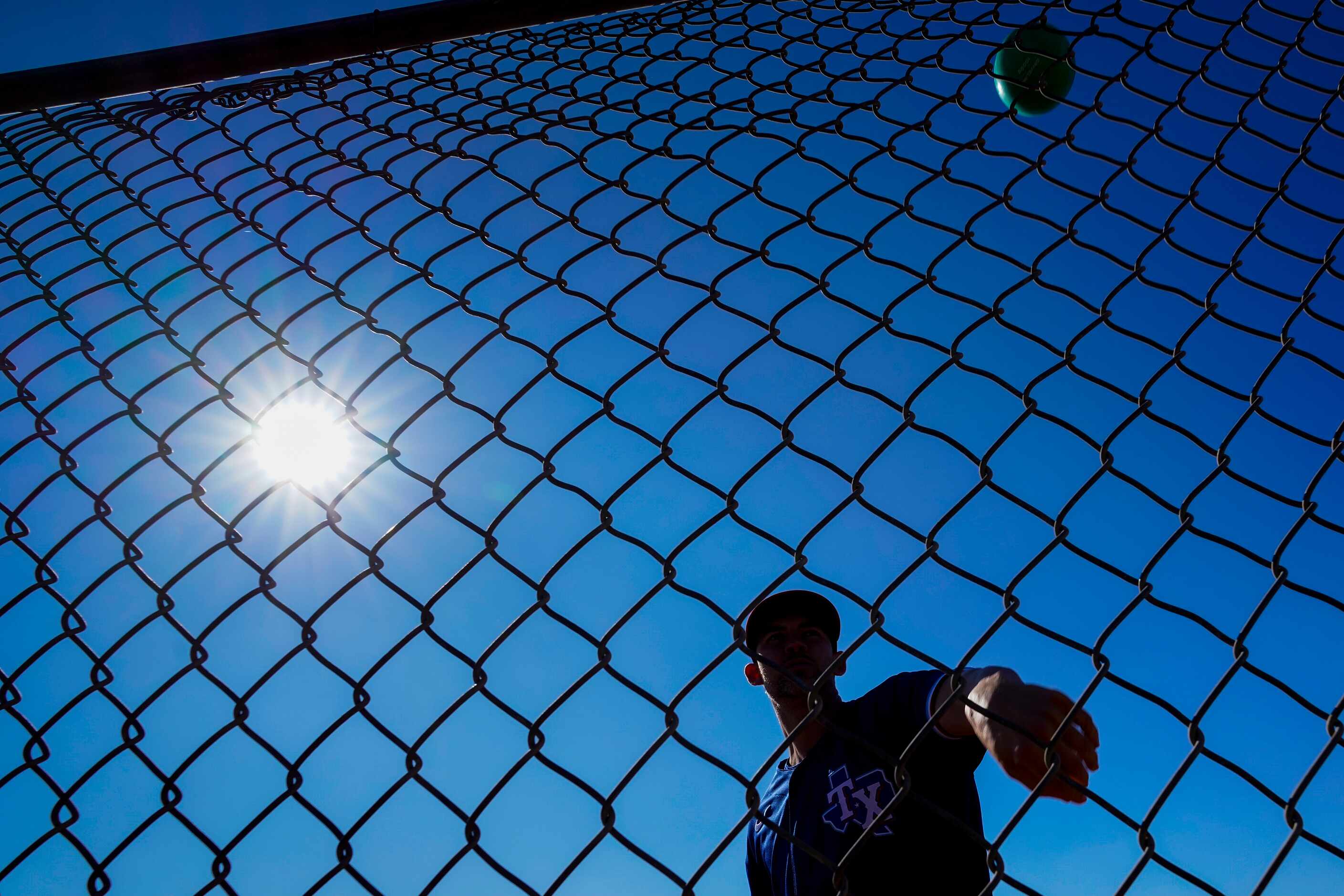 Texas Rangers pitcher Mike Minor tosses a ball into a fence during the first spring training...