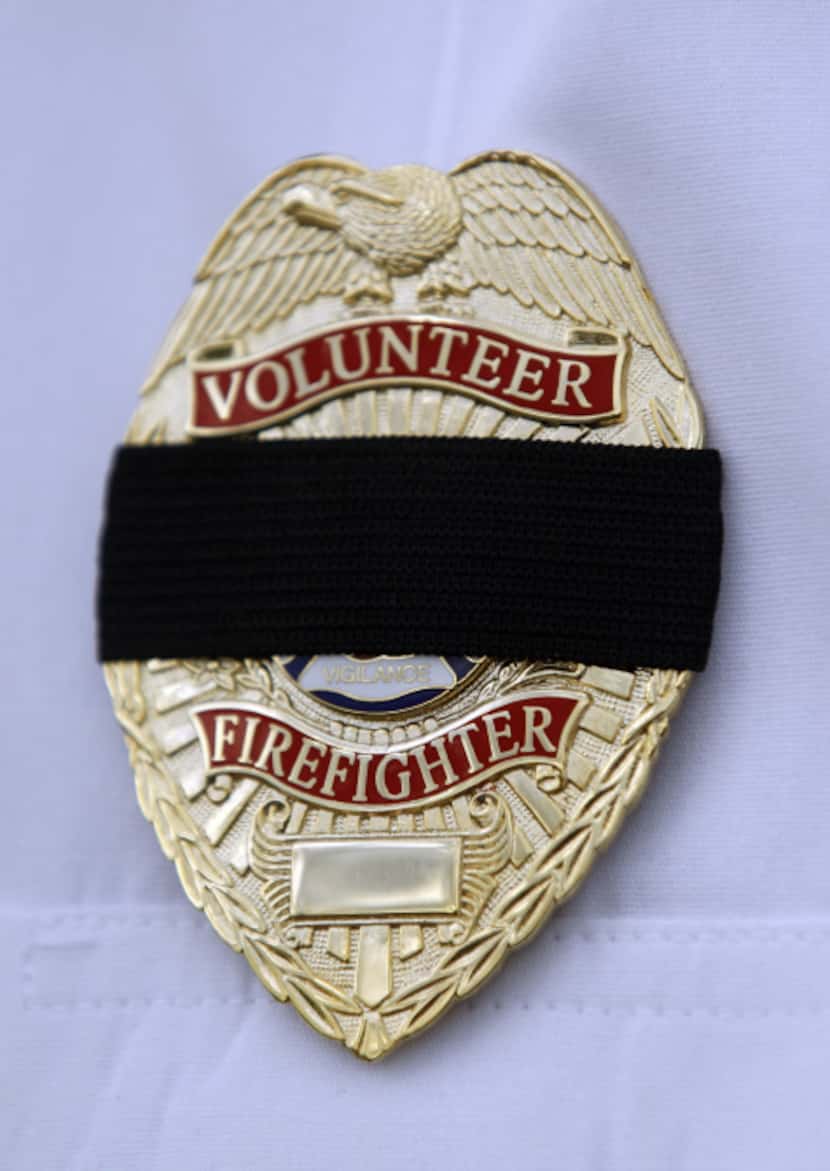 A black mourning band covers the badge of a volunteer firefighter participating in...