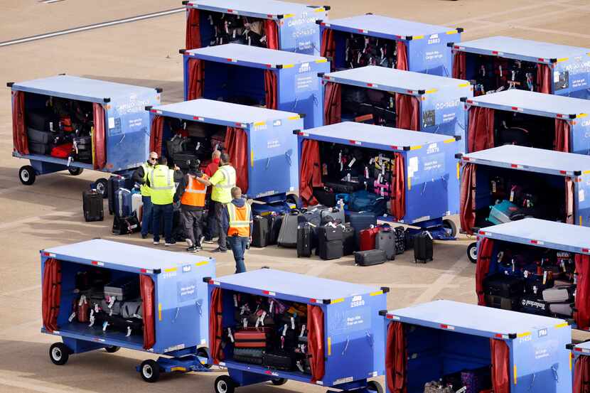 Southwest Airlines employees sort through luggage stored in carts on the Dallas Love Field...