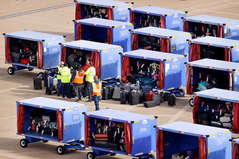 Southwest Airlines employees sort through luggage stored in carts on the Love Field tarmac,...