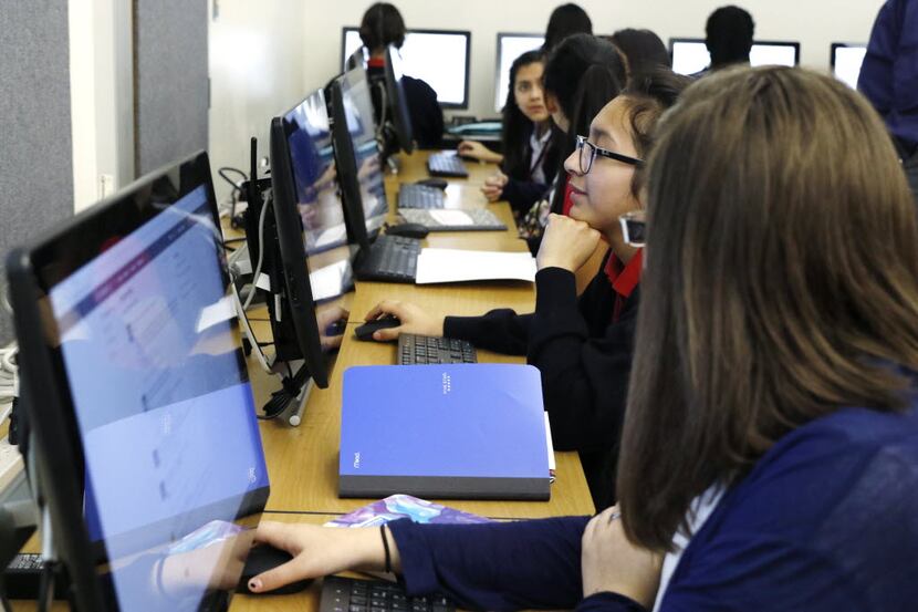 Joselin Barbosa, 14, center, works on a computer in her business information management...