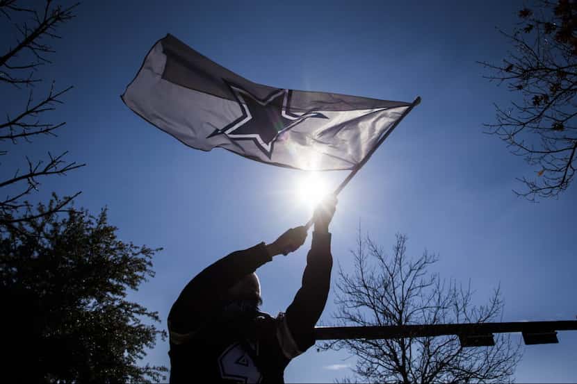 Ramon Barrera of Coppell waves a Dallas Cowboys flag in the parking lot before an NFL game...