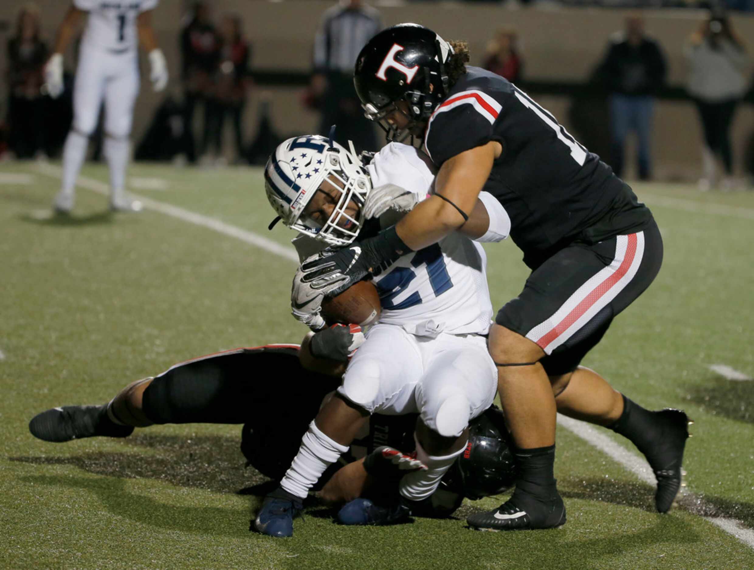 Richland's Brandon Johnson (21) is tackled by Trinity's Zeb Miller (27), bottom, and Zion...