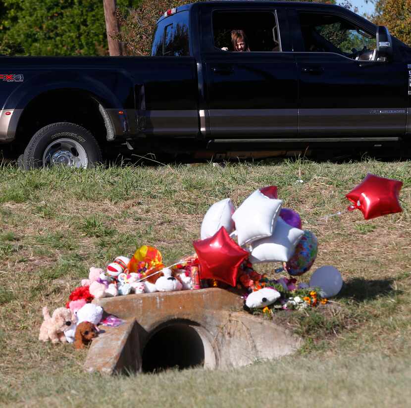 Miley Grahmann, 8, peeks out a truck to see a small memorial in the area where Sherin...