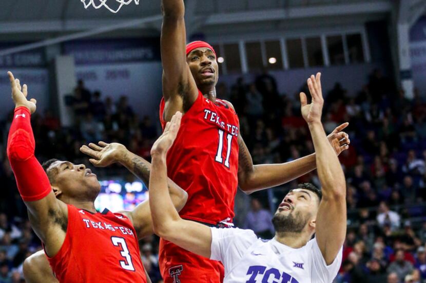 TCU Horned Frogs guard Alex Robinson (25) shoots as he is defended by Texas Tech Red Raiders...