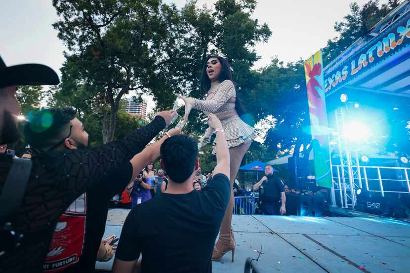 Audience members tip Valentina Diamond Doll during a drag performance at the Texas Latinx...