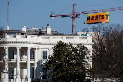 Greenpeace protesters unfurled a banner that read "Resist" atop a crane several blocks north...