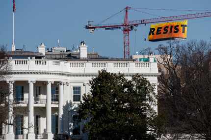 Greenpeace protesters unfurled a banner that read "Resist" atop a crane several blocks north...