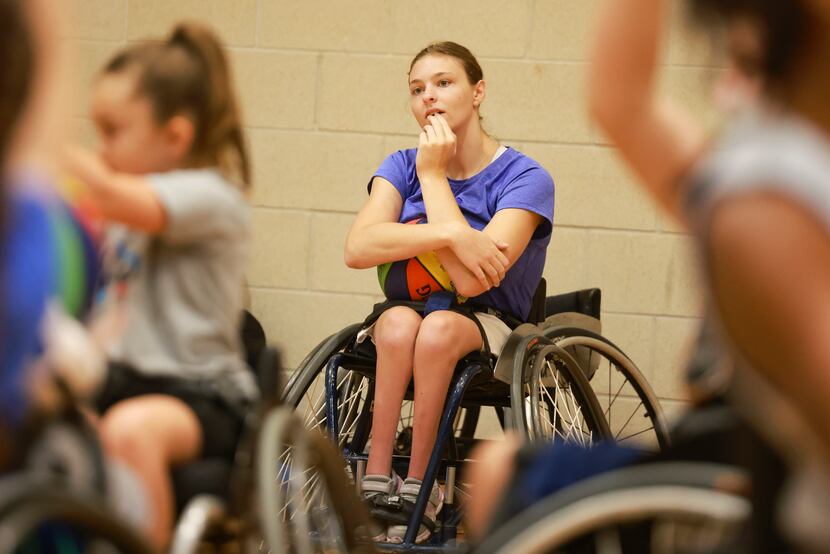 Abbie Counts, a Dallas Junior Wheelchair Mavericks varsity player, watches youngsters warm up.