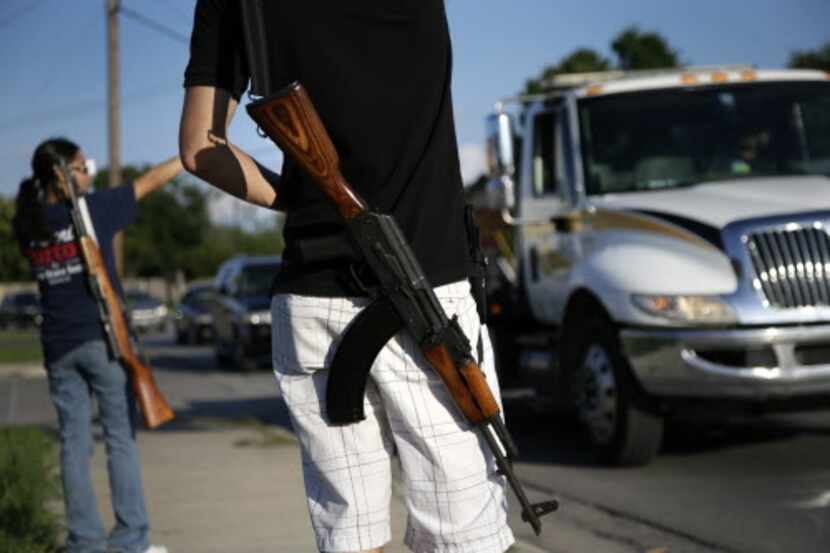 Kory Watkins of Open Carry Tarrant County lets his AK-47 do some of his talking during a...