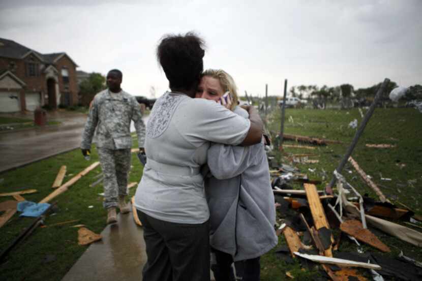 Yuomiko Paige (left) hugs neighbor Doris Sparks as Sparks talks on the phone about storm...