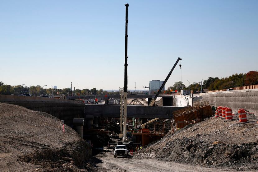  Construction workers work on a depressed section of the LBJ Freeway managed toll lanes in...