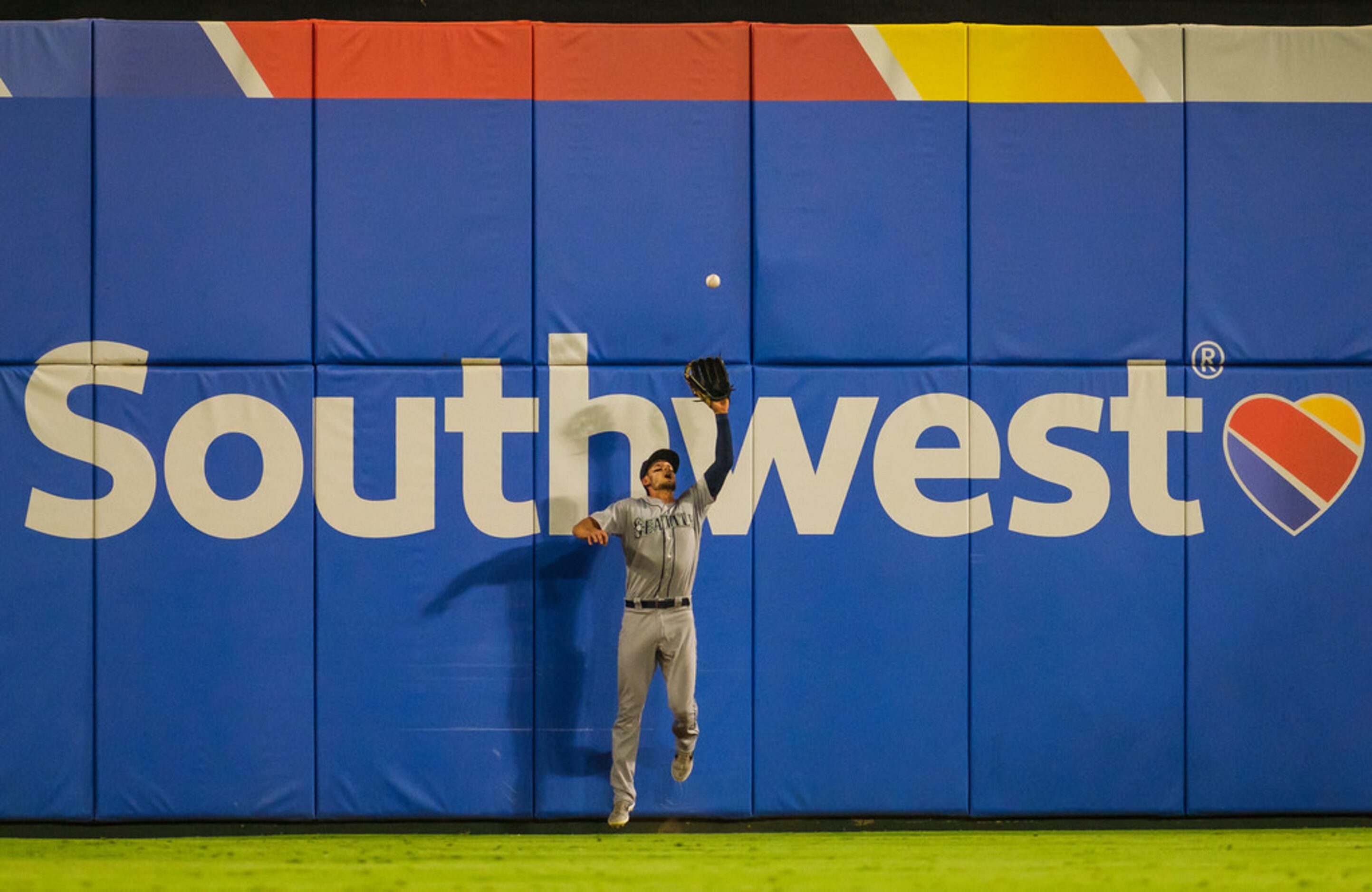 Seattle Mariners left fielder Ryan Court leaps to catch a ball off the bat of Texas Rangers...