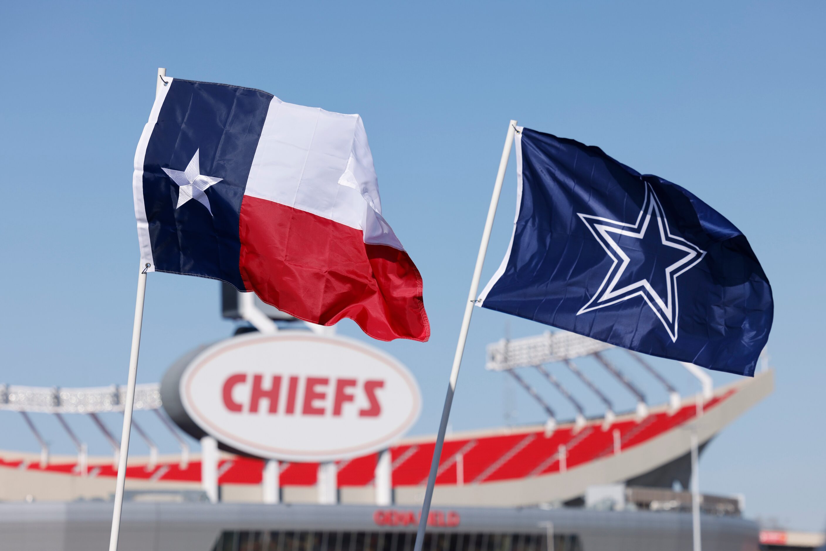 A Texas flag and Cowboys flag fly over tailgaters before an NFL football game between the...