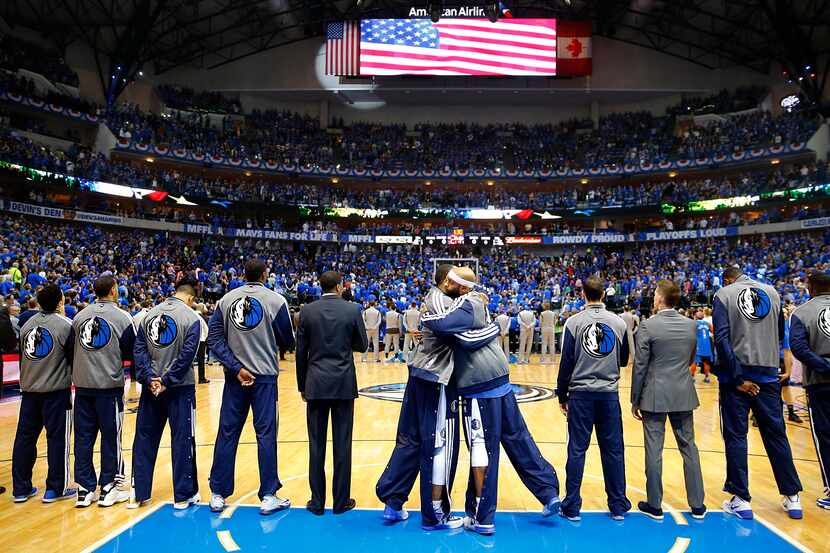 Dallas Mavericks players hug one another during the National Anthem before the NBA Western...