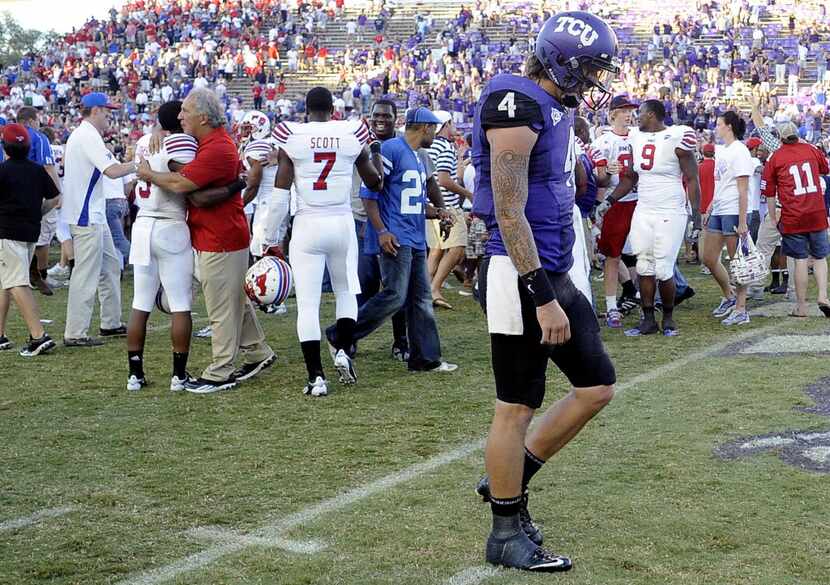 TCU quarterback Casey Pachall (4) walks off the field as SMU players and fans celebrate...