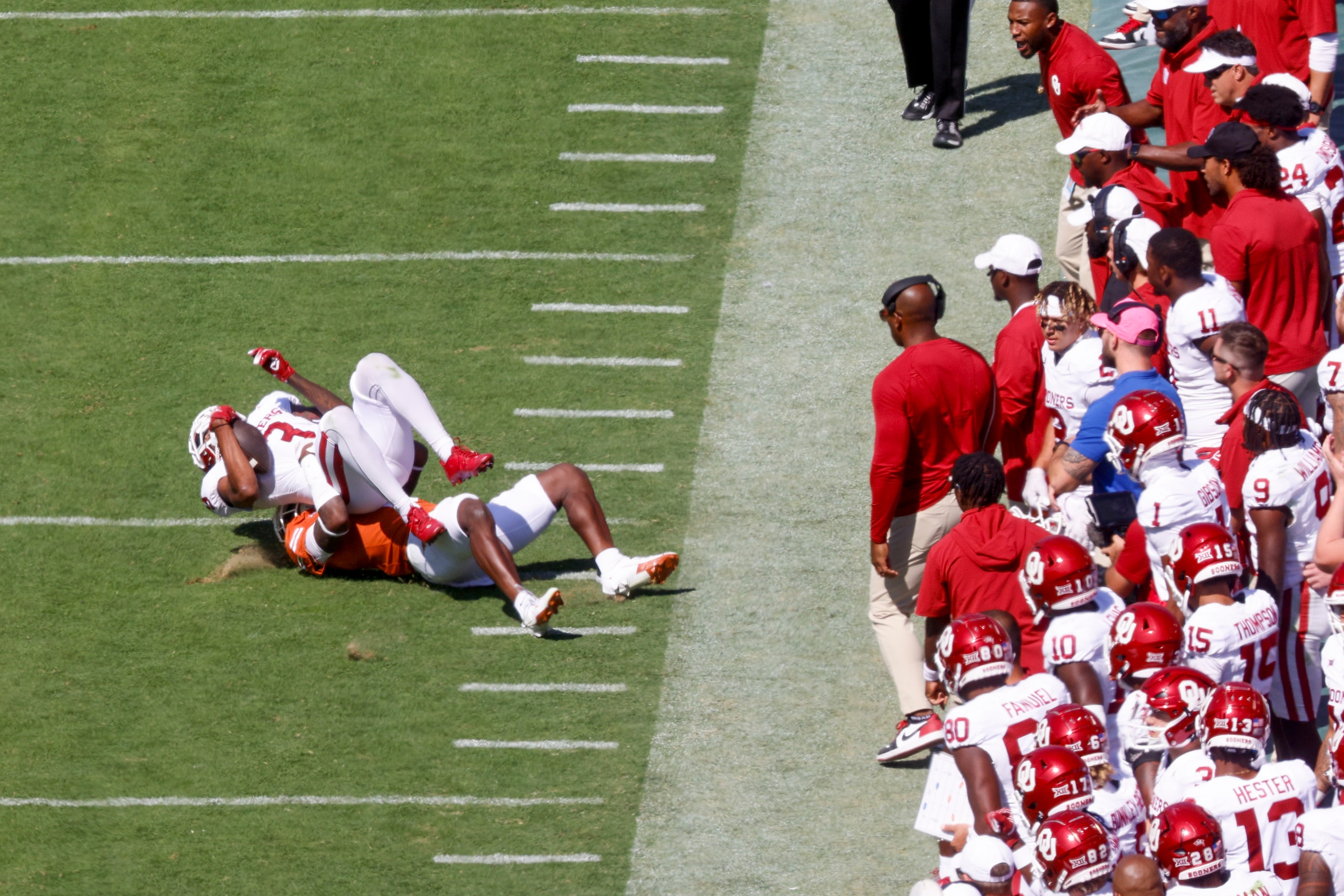 Texas defensive back Terrance Brooks (bottom) tackles Oklahoma wide receiver Jalil Farooq...