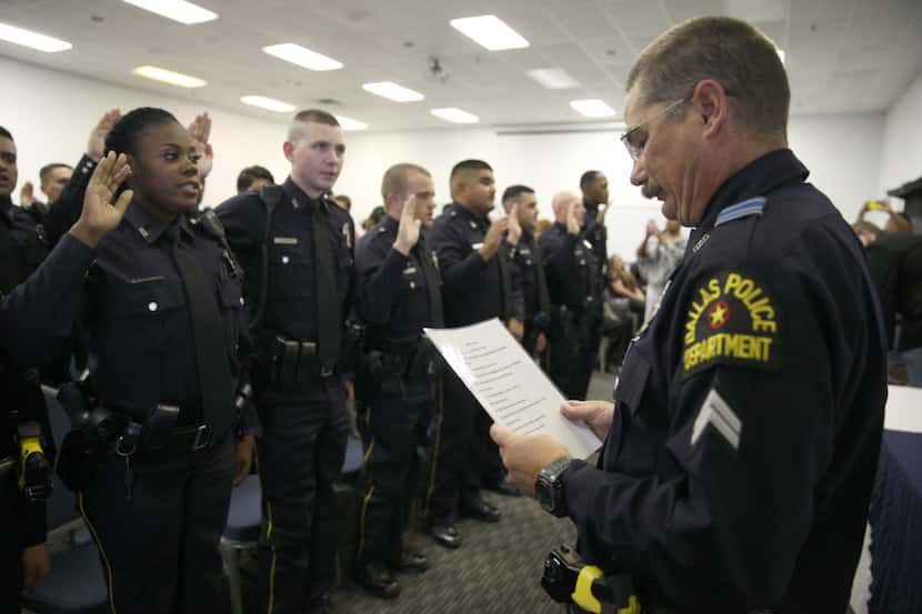 New Dallas police officers take an oath after receiving their badges on Thursday, August 18,...