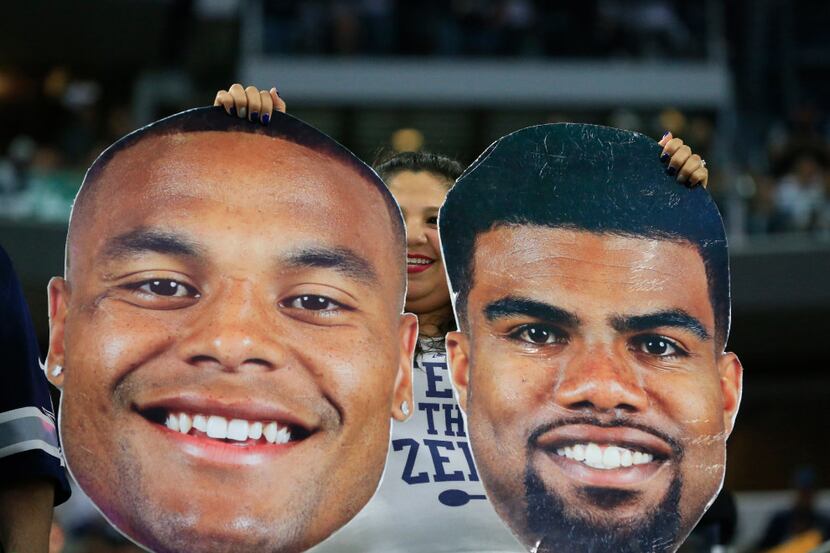 A Dallas Cowboys fans holds face posters of Dallas Cowboys quarterback Dak Prescott and...
