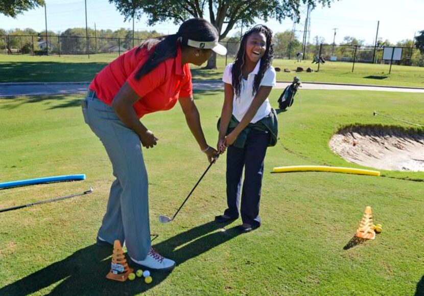 
Maulana Dotch helps Shanya Cherry, 9, with her golf swing during a lesson for students from...