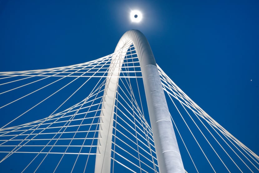 Darkness falls on the Margaret Hunt Hill Bridge as the sun is covered by the moon during a...