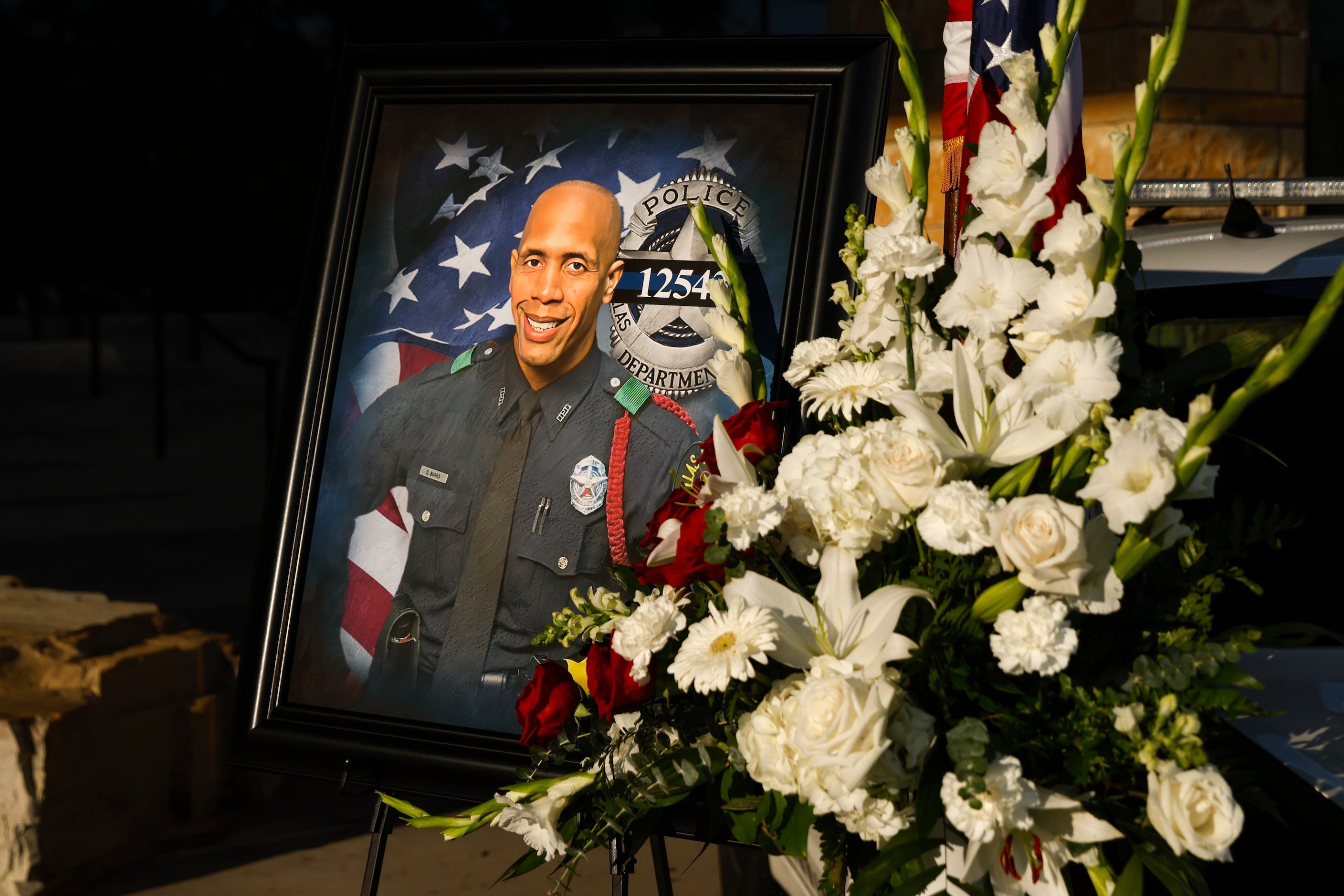 A portrait of Dallas police Officer Darron Burks is seen alongside a bouquet of flowers set...