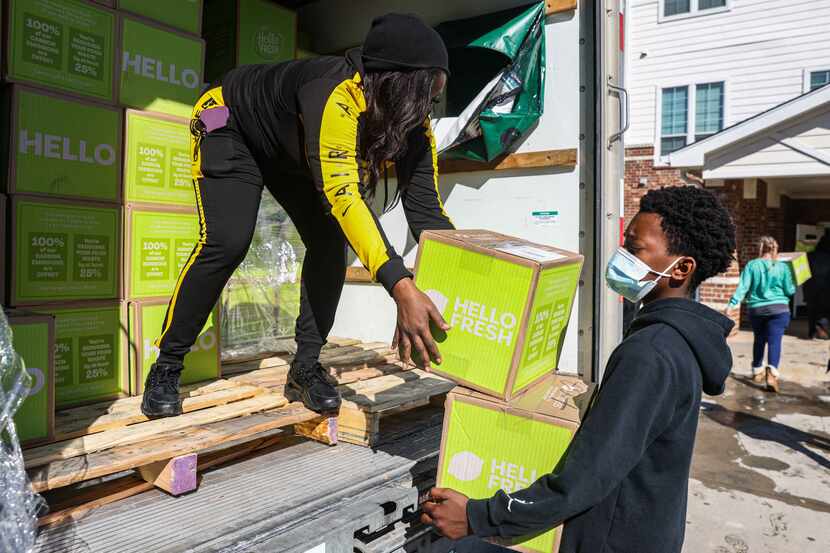 Local volunteer Sonya Tubbs with the help of Marcus Thomas, 13, bring boxes of food for the...