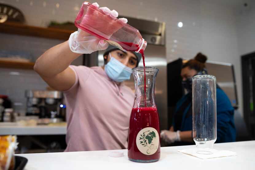 Partner Angel Diaz pours an Apollo juice into a serving bottle at the juice bar inside Taste...