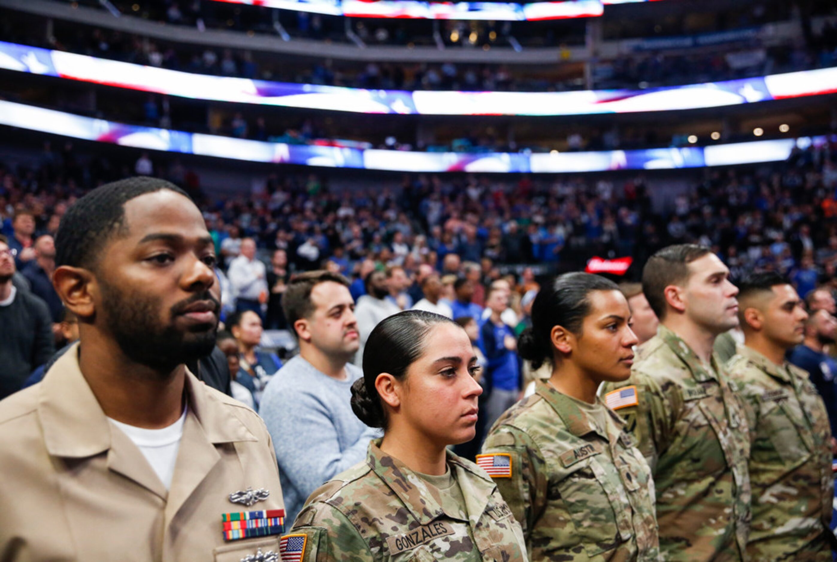 Veterans and members of the armed forces fill court-side seats for an NBA game between the...